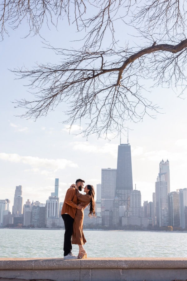 engaged couple poses for a photo in front of the chicago skyline