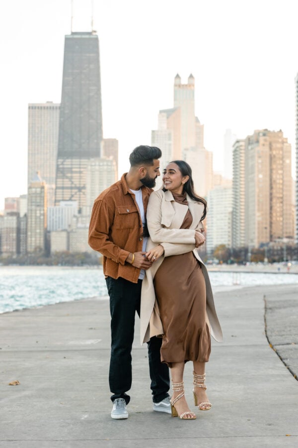 engaged couple poses for a photo in front of the chicago skyline